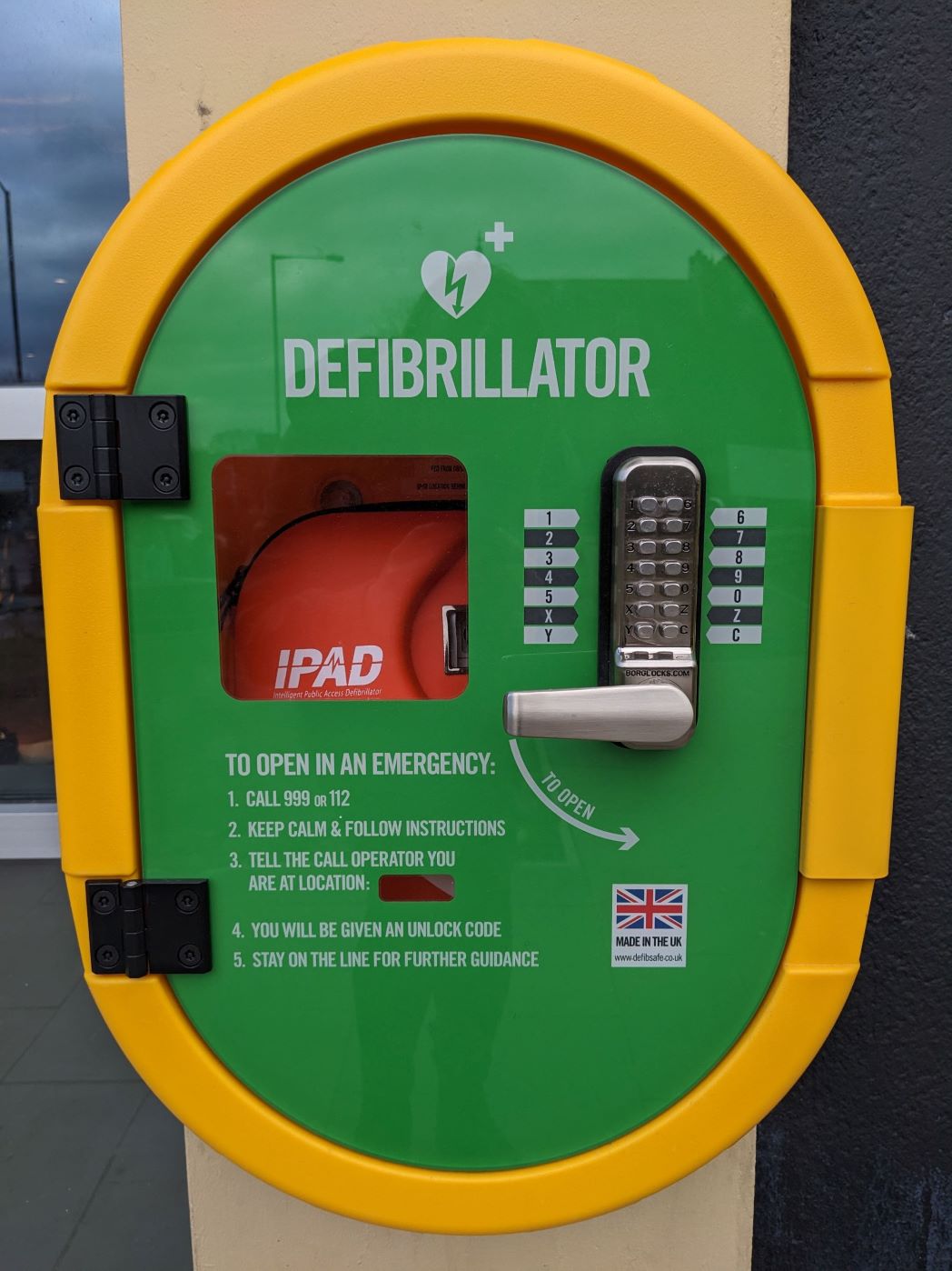 A picture of the public facing AED mounted on the wall of Senate House.
